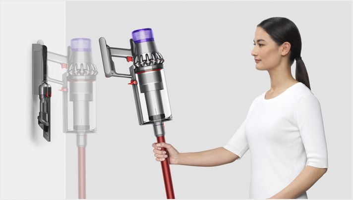 Woman placing Dyson Outsize vacuum into wall charging dock Woman placing Dyson Outsize vacuum into wall charging dock